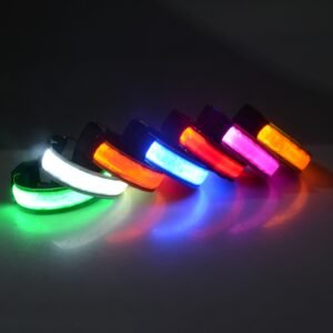 Six LED Safety armbands (USB rechargeable) glow in green, white, red, blue, orange, and pink on a dark surface, their vibrant lights casting reflections—perfect for running or cycling at night.