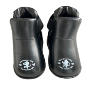 A pair of black Revolution Sparing Feet boots featuring the Taekwon-Do logo and a white lion emblem printed on top of each foot.