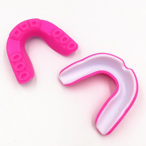 Two Gum Shield - Pink and White mouthguards rest on a white surface, one displaying its textured inner side, the other revealing a smooth white interior.